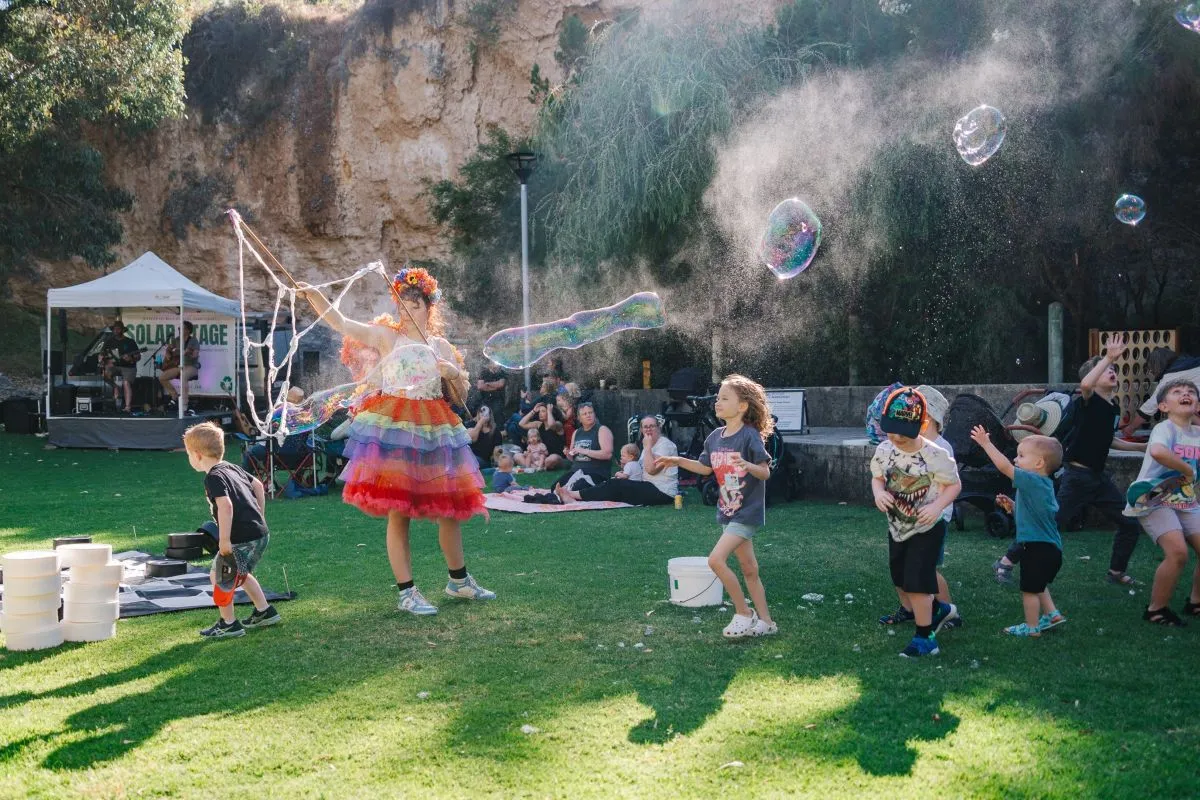Children playing with large bubbles at an outdoor community event